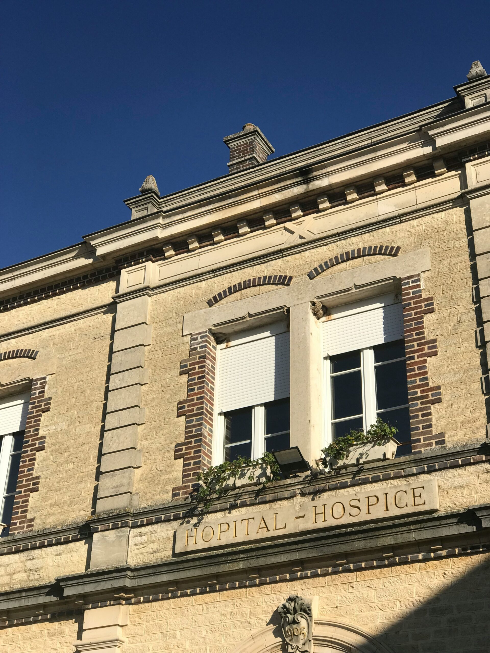 Old building with "Hospital and Hospice" engraved below upper story windows.
