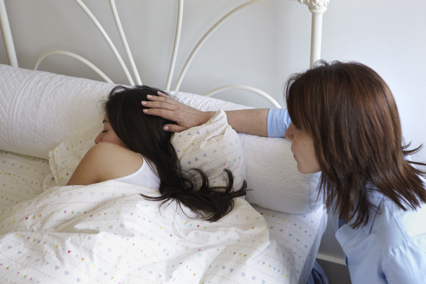 a woman comforting another woman at the bedside showing types of grief