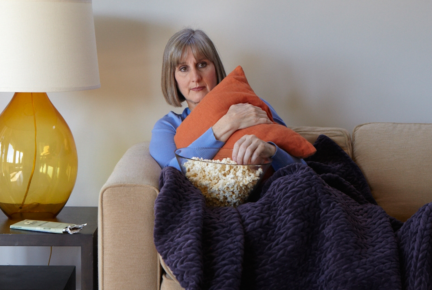 a woman with dementia sitting on a couch eating popcorn