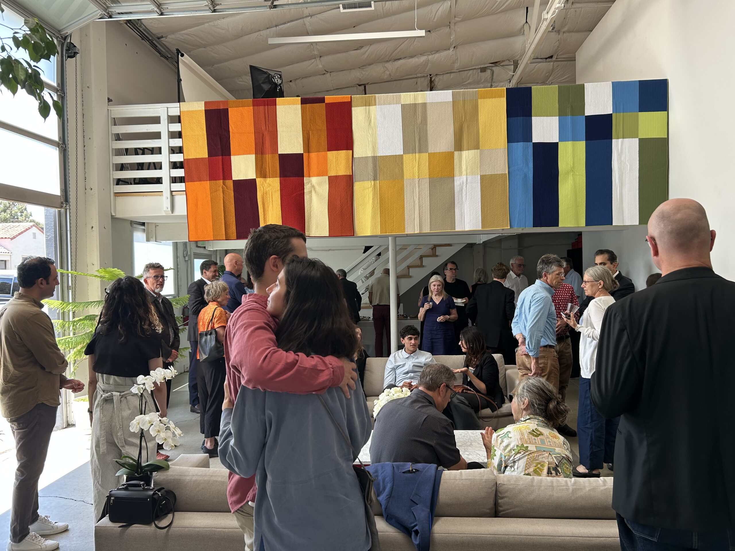a woman and man are embracing in front of a colorful banner at a memorial service