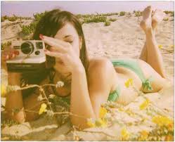 A vintage photo of young girl on a beach taking a picture with a camera regarding her story of a death