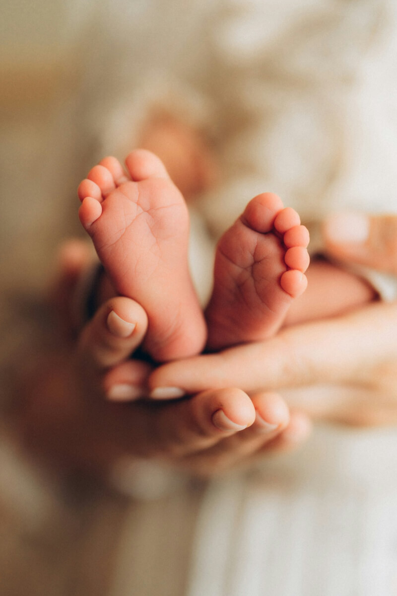 a parent's hands holding an infants feet illustrating quotes about infant loss