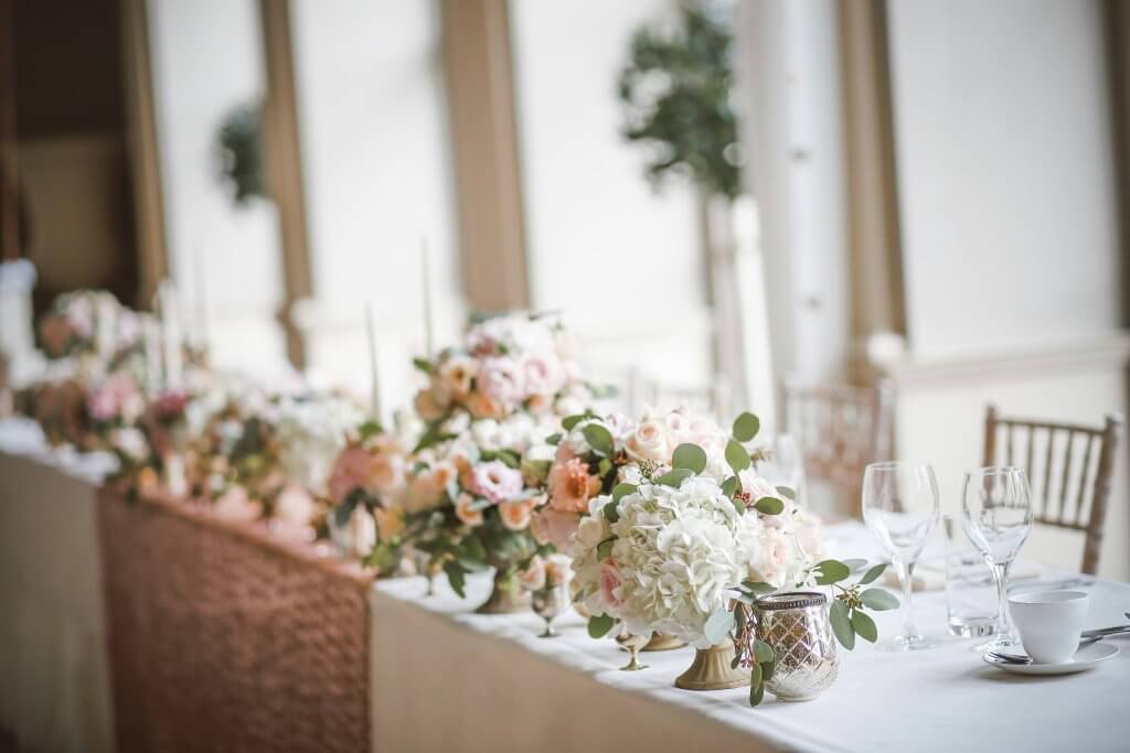 A table of flowers arrangements all lined up for an over the top memorial service display