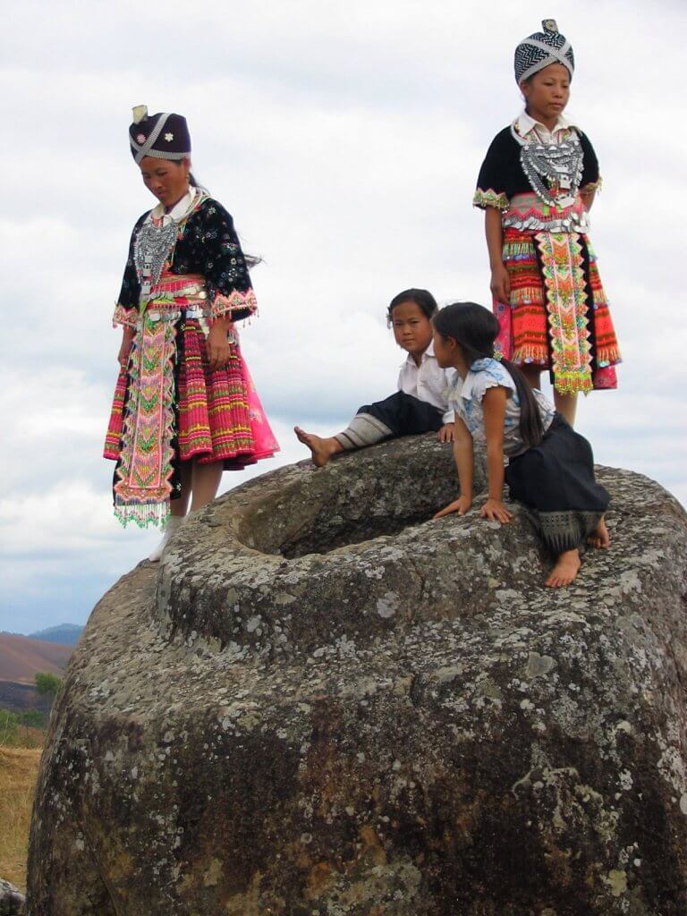 Four Hmong girls climb atop a megalith that might have been used in mortuary practices at Laos Plain of Jars, Site 1.