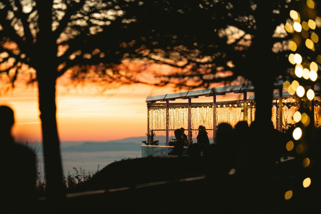 Outdoor memorial venue overlooking the mountains at sunset, decorated with string lights