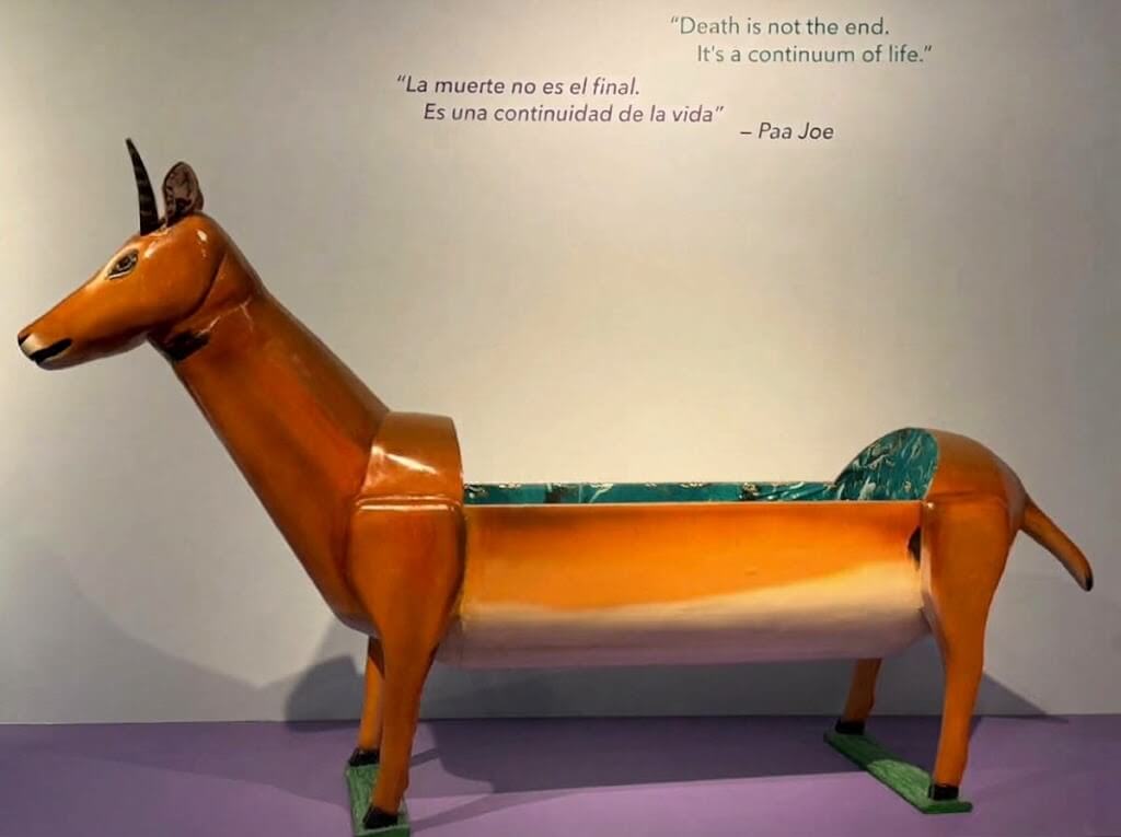 An antelope-shaped fantasy coffin by Paa Joe on display at a museum exhibit under a quote about death and life.